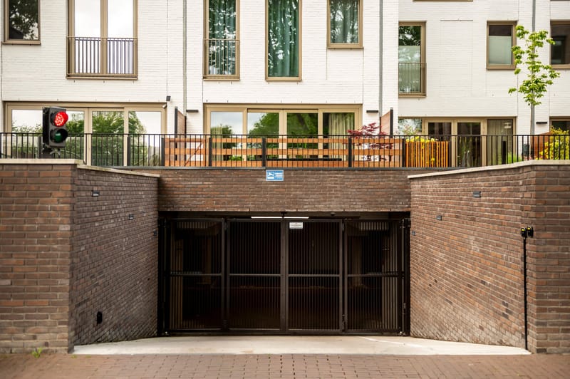 Gesloten garagepoort onder het appartementencomplex, in de kleur van de balkonhekken