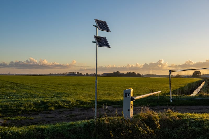 Slagboom met zonnepanelen op een mast aan de rand van een weiland