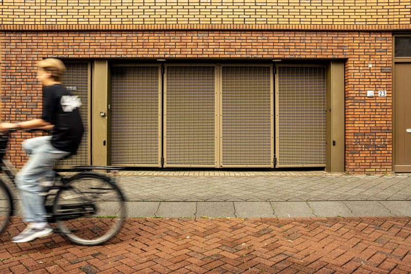 Fietser rijdt langs een gesloten speedgate in de gevel van een woongebouw