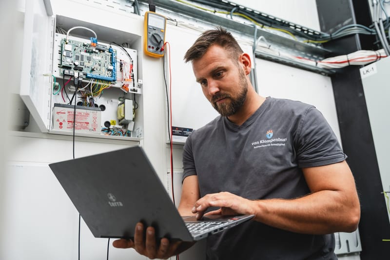 Monteur controleert een besturingskast met een laptop