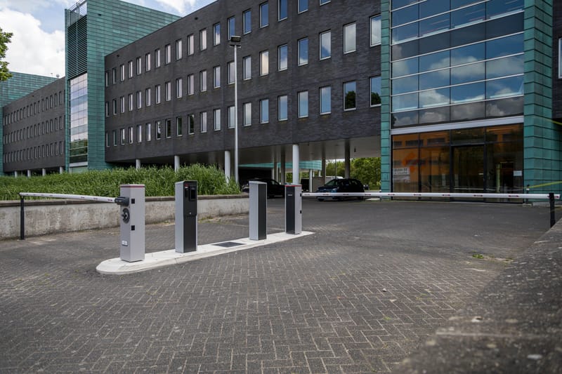 Verkeerseiland met toegangszuilen en slagboom bij de inrit van Green Capitol