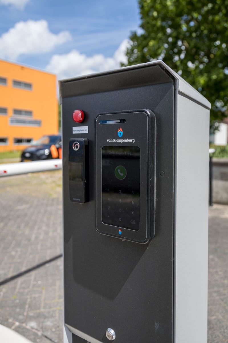 Toegangszuil met intercom en lezer bij de inrit van een kantorencomplex