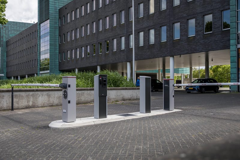 Toegangszuilen en slagboom bij de inrit van een kantoorparkeerterrein