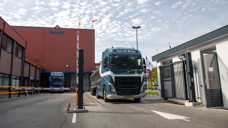 Tankwagen rijdt een fabrieksterrein op, langs de geopende slagboom
