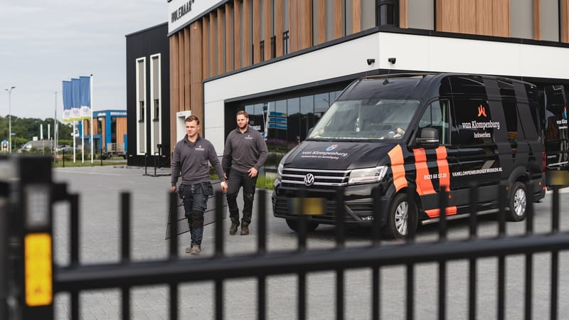 Twee monteurs van Van Klompenburg lopen bij hun bedrijfsbus