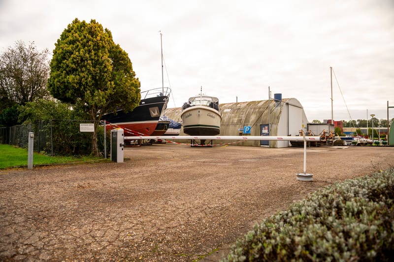 Geopende slagboom over de toegangsweg van een jachthaven