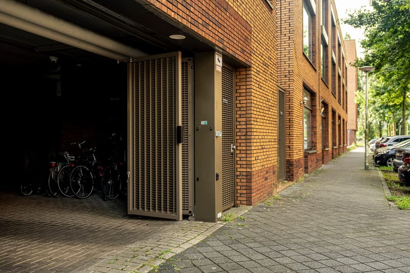 Geopende poort naar de fietsenstalling van een woongebouw