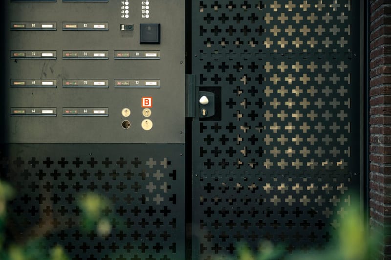 Intercom met belpanel en lezer in een postkastenwand bij de entree van een woongebouw